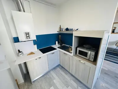 a small kitchen with white cabinets and a microwave at Grand Studio terrasse vue sur mer et parking in Ajaccio