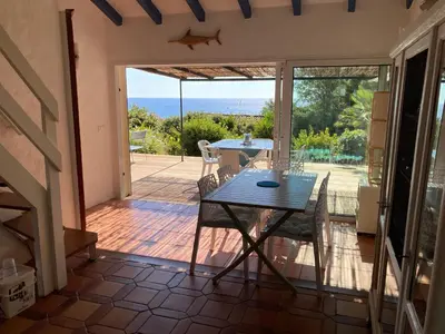 a dining room with a table and a view of the ocean at VILLA LES GORGONES - Corse du Sud - Vue mer - 200m plage in Zonza