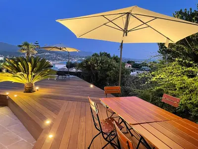a wooden deck with a table and an umbrella at Villa Thamyris Porticcio Ajaccio Corse in Grosseto-Prugna