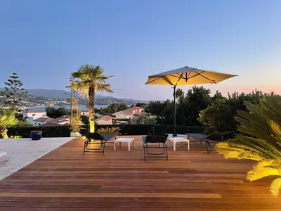 a group of chairs and an umbrella on a wooden deck at Villa Thamyris Porticcio Ajaccio Corse in Grosseto-Prugna