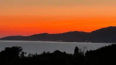 a sunset over the water with mountains in the background at Villa Thamyris Porticcio Ajaccio Corse in Grosseto-Prugna