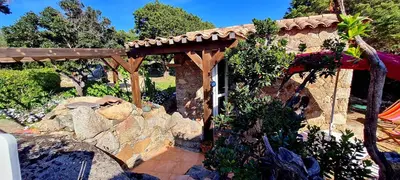 a stone building with a wooden pergola at La Bergerie de Pauline - Bord de mer, vue unique in Pianottoli-Caldarello