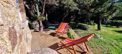 two lawn chairs and a table in a yard at La Bergerie de Pauline - Bord de mer, vue unique in Pianottoli-Caldarello