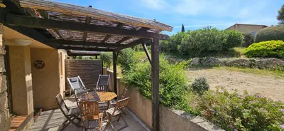 a patio with a table and chairs under a pergola at Mini Caseddu T2, Piscine & vue mer, Alba Rossa N11 in Serra-di-Ferro