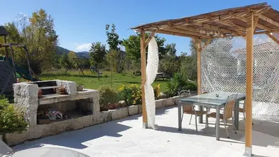 a patio with a table and a stone fireplace at Villa Piazzola in Petreto-Bicchisano