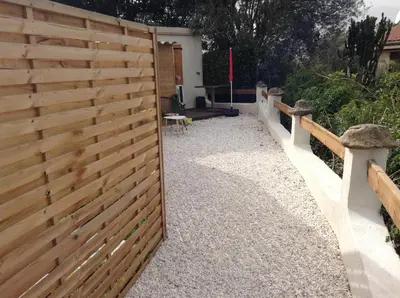 a wooden fence in a garden with a pathway at la loggia in Porto-Vecchio