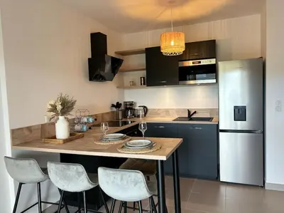 a kitchen with a table with chairs and a refrigerator at Bel appartement T2 proche centre-ville et port in Porto-Vecchio