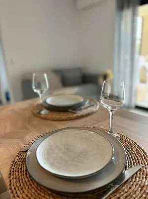 a wooden table with two plates and wine glasses at Bel appartement T2 proche centre-ville et port in Porto-Vecchio