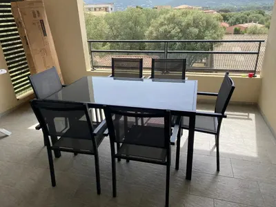 a dining room table with four chairs and a balcony at Bel appartement T2 proche centre-ville et port in Porto-Vecchio