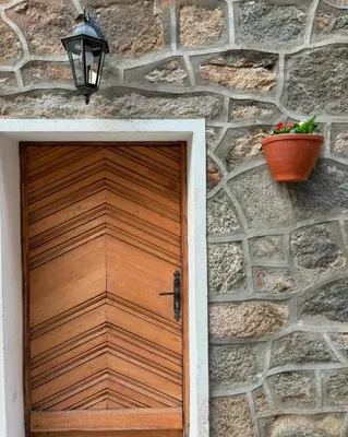a wooden door on a stone wall with a flower pot at HÖTEL U SANTA MARIA in Olmeto