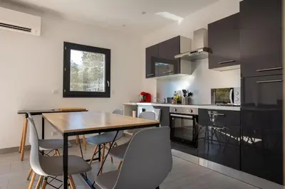 a kitchen with black cabinets and a wooden table and chairs at Casa Léa in Sollacaro