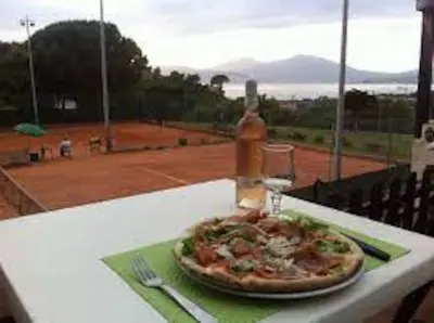 a pizza on a table with a bottle and a glass at Location Appartement Porticcio in Grosseto-Prugna