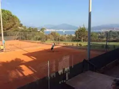a person is playing tennis on a tennis court at Location Appartement Porticcio in Grosseto-Prugna