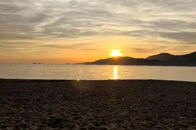 a sunset on the beach with the sun setting at Location Appartement Porticcio in Grosseto-Prugna