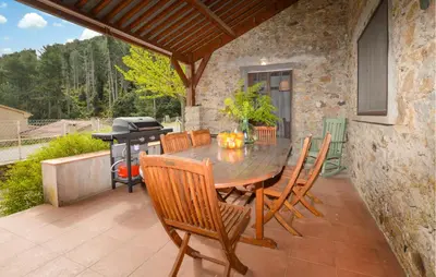 a wooden table and chairs on a patio with a grill at 2 Bedroom Stunning Home In Popolasca in Popolasca