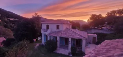 a small white house with a sunset in the background at Mare e Monti Chez Thomas et Magali in Vico
