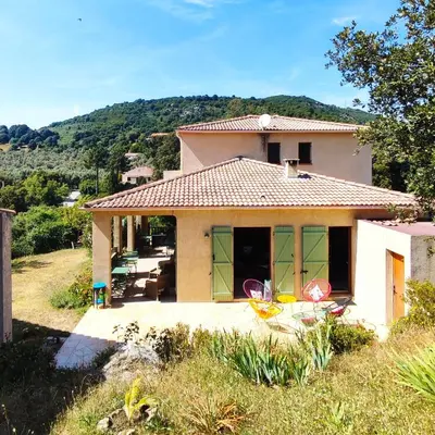 a house with green doors and chairs in a yard at Mare e Monti Chez Thomas et Magali in Vico