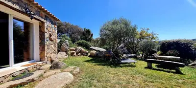 a stone house with a bench in a yard at Bergerie A Sapara in Pianottoli-Caldarello