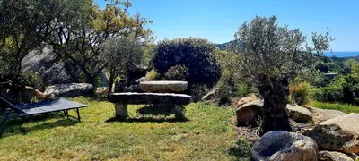 a garden with a bench and some rocks and trees at Bergerie A Sapara in Pianottoli-Caldarello