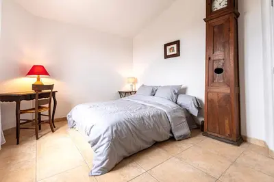 a bedroom with a bed and a wooden grandfather clock at Bergerie Piattone - Maison avec grand jardin in Pianottoli-Caldarello
