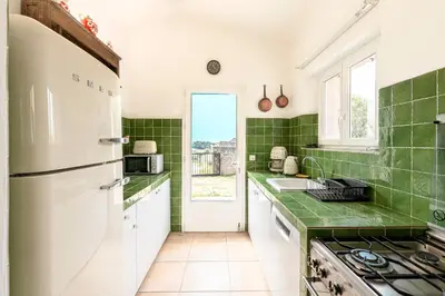 a kitchen with green tiles and a white refrigerator at Bergerie Piattone - Maison avec grand jardin in Pianottoli-Caldarello