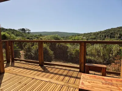 a deck with a bench and a view of the mountains at Chalet maisonette dans hameau calme in Bonifacio