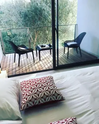 a room with a couch and a balcony with chairs at Villa La Rondina vue mer, piscine et plage à pied. in Zonza