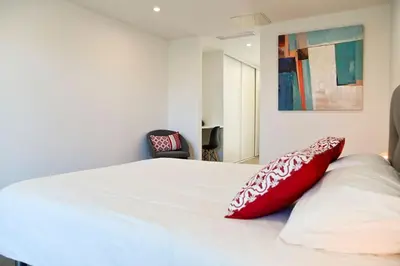a bedroom with a bed with a red pillow on it at Villa La Rondina vue mer, piscine et plage à pied. in Zonza