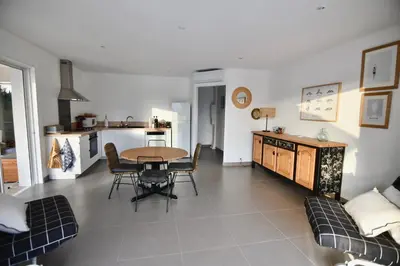 a living room with a table and chairs and a kitchen at Appartement 60m2 avec piscine privée dans villa in Oletta
