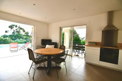 a kitchen and dining room with a table and chairs at Appartement 60m2 avec piscine privée dans villa in Oletta