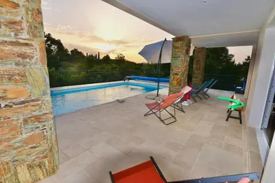 a patio with a pool and chairs and an umbrella at Appartement 60m2 avec piscine privée dans villa in Oletta