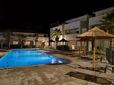 a swimming pool at night with chairs and an umbrella at T3 vue mer direct plage clim N79 in Linguizzetta