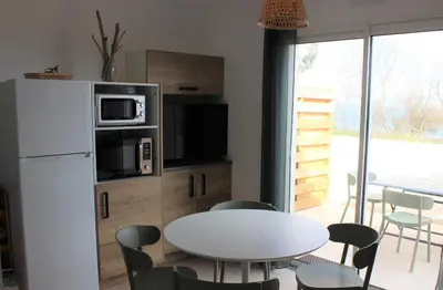 a kitchen with a table and a white refrigerator at T3 vue mer direct plage clim N79 in Linguizzetta