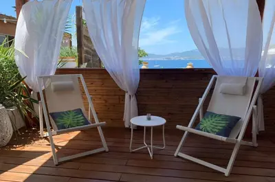 two chairs and a table on a deck with a view of the ocean at Résidence CasaBianca Porticcio - Aïtone in Porticcio
