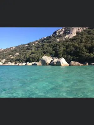 a body of water with rocks in front of a mountain at Appartement proche des plages in Porto-Vecchio