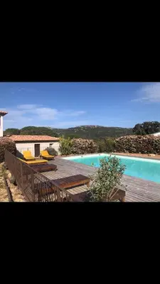 a view of a swimming pool with a deck and a house at Appartement proche des plages in Porto-Vecchio