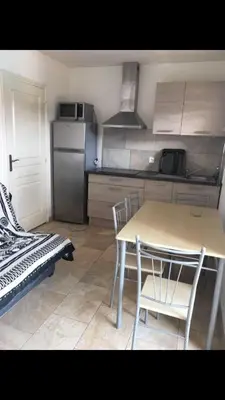 a kitchen with a table and chairs and a refrigerator at Appartement proche des plages in Porto-Vecchio