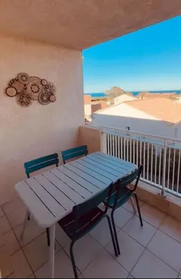 a blue table and two chairs on a balcony with a table and a window at Charmant T2 rénové avec vue mer in Cervione