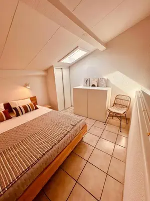 a bedroom with a bed and a chair in a room at Charmant T2 rénové avec vue mer in Cervione