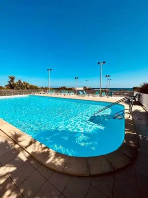 a large swimming pool with blue water and lights at Charmant T2 rénové avec vue mer in Cervione