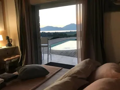 a bedroom with a view of a pool through a window at Villa Pierre SANTONI in Porticcio