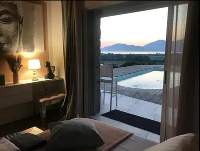 a bedroom with a door open to a balcony at Villa Pierre SANTONI in Porticcio
