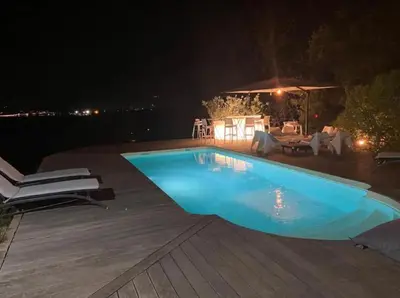 a swimming pool at night with a table and chairs at Villa Pierre SANTONI in Porticcio