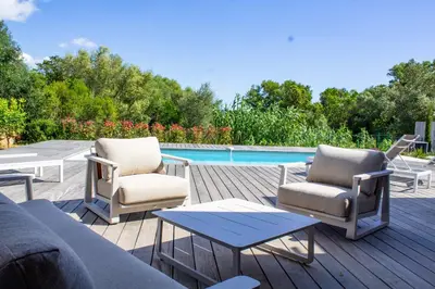 a patio with a couch and chairs and a pool at Villa Arinella Villata Di Capicciola in Sainte-Lucie de Porto-Vecchio