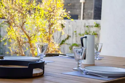 a wooden table with plates and wine glasses on it at Villa Arinella Villata Di Capicciola in Sainte-Lucie de Porto-Vecchio
