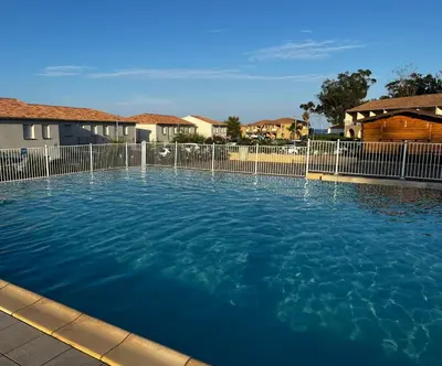 a swimming pool with a fence and blue water at Appartement 2 pièces bord de mer in Linguizzetta