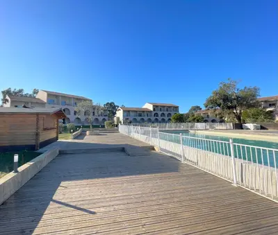 a boardwalk in front of a building and a pool at Appartement 2 pièces bord de mer in Linguizzetta