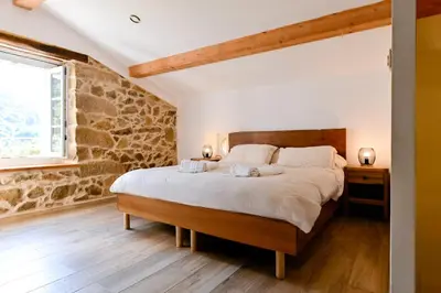 a bedroom with a large bed and a stone wall at Particasgiu - Agritourisme in Vico