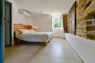 a bedroom with a bed and a stone wall at Particasgiu - Agritourisme in Vico