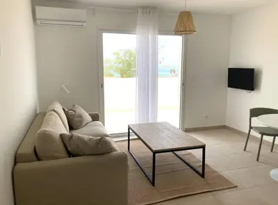 a living room with a couch and a table at Studio 2 personnes vue mer et pieds dans l'eau in Linguizzetta